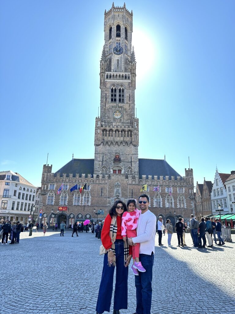 a husband and wife and their daughter taking a picture behind a tall building