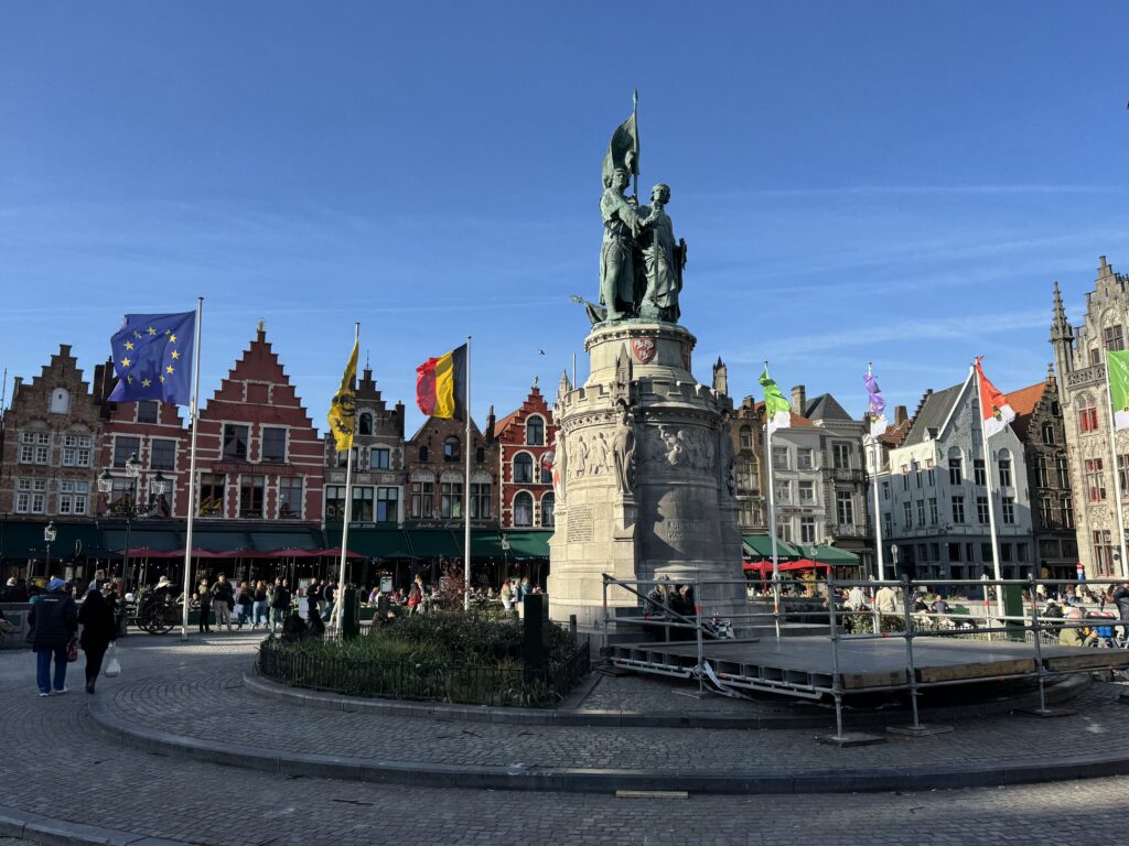A mounted statue of a man is prominently displayed in a square, with various flags waving around it.