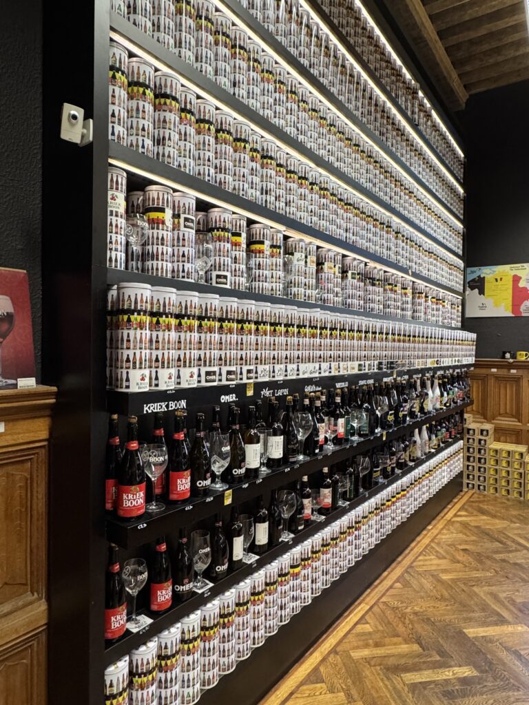 A shelf filled with various beer cans, neatly arranged in a room with neutral-colored walls.